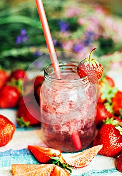 A glass of strawberry smoothie on a wooden background. Strawberr