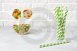 Glass with striped green drinking straws brick wall background