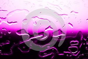 Glass surface with spilled water, bright pink color, shiny drops texture, wet background, light purple gradient, close up