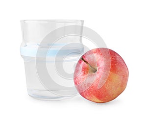 Glass with sweet fructose syrup and ripe apple on white background