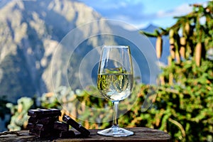 Glass of swiss or savoy dry white wine, pure chocolate with Alpine mountains peaks on background