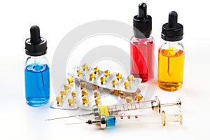 Syringes with medication, blister packs with pills and bottles with colored fluid on white background