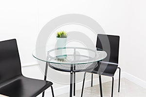 A glass table and black chairs in the Scandinavian style in the interior of a bright modern apartment. Kitchen area