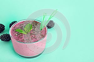 Glass of tasty blackberry smoothie with chia seeds and straws on turquoise background.