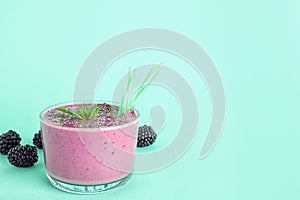 Glass of tasty blackberry smoothie with chia  and straws on turquoise background. Space for text