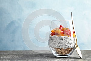 Glass of tasty chia seed pudding with granola, persimmon and pomegranate on table