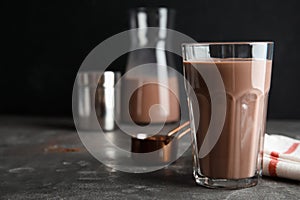 Glass with tasty chocolate milk on gray table