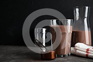 Glass with tasty chocolate milk on gray table, space for text