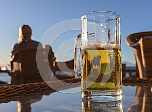 Glass of tasty cold beer, standing on a table of a beach bar.