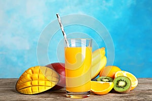 Glass with tasty mango juice and fresh fruits on table