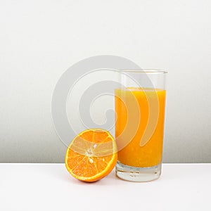 The glass of tasty pure orange juice and fresh orange half