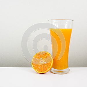 The glass of tasty pure orange juice and fresh orange half