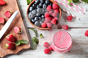 Glass with tasty raspberry smoothie and berries on wooden table