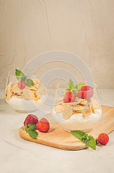 Glass of tasty strawberry dessert/Smoothies with corn flakes decorated mint and strawberry on a white background with copyspace