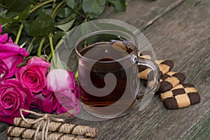 Glass of tea and cookies on a plate with a bouquet of roses