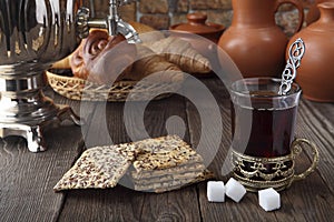 A glass of tea with cracker and buns near the samovar. Retro stylized photo.