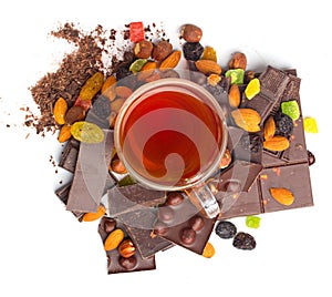 Glass tea cup and dried fruits and chocolate piles with filberts. Dessert food photo