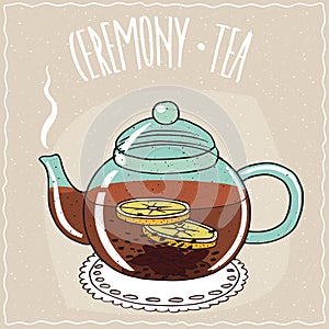 Glass teapot with black tea with lemon