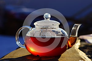 Glass teapot with black tea. The sun is reflected in the teapot. Boiling water, hot tea. Drops on a glass teapot. Tea on the