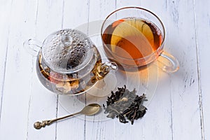 Glass teapot with blooming green tea and cup of tea