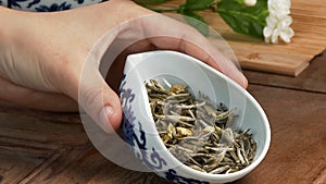 Glass teapot with blooming tea flower inside against wooden background Chinese green tea leaves close up in traditional