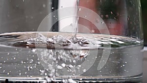 glass teapot close-up being filled with a stream of water