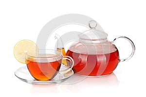 Glass teapot and cup of black tea with lemon slice