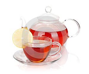 Glass teapot and cup of black tea with lemon slice