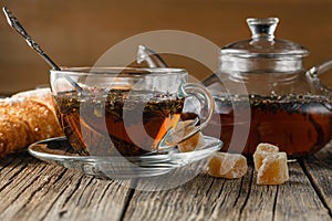 Glass teapot and cup with herbal tea on old wooden table