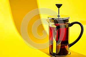 Glass teapot with hot hibiscus tea Fresh brewed spicy fruit tea with herbs, rose flowers, hot healthy drink on yellow background