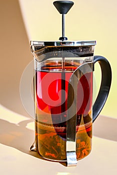 Glass teapot with hot hibiscus tea Fresh brewed spicy fruit tea with herbs, rose flowers, hot healthy drink on yellow background