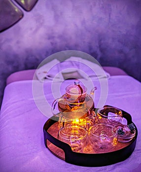 A glass teapot over a candle before a massage procedure in the salon