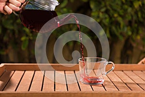 Glass teapot pouring fruit tea into cup