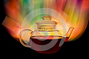 Glass teapot with red tea and fire looking background