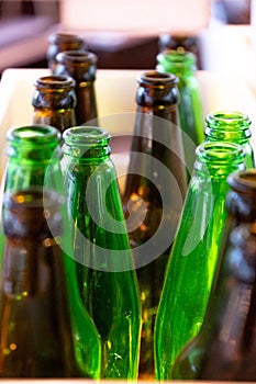 Green and brown glass bottle tops. Many empty glass bottles. Polished clean glass texture of retro shaped beer bottles.