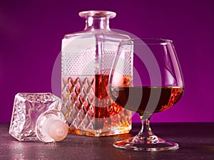 glass textured square bottle and glass goblet with amber alcohol brandy scotch whiskey. violet. Horizonal