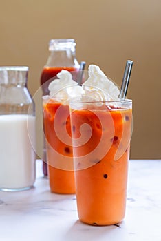 A glass of Thai iced tea top with Whipped cream