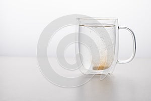Glass thermo mug of water-soluble effervescent orange tablet on a white background