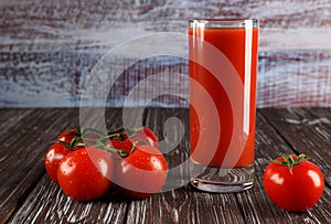 A glass of tomato juice and juicy, red tomatoes.