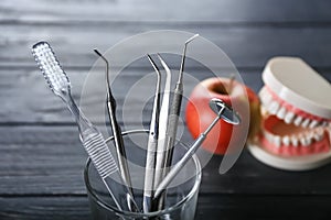 Glass with toothbrush and dental instruments on dark wooden table
