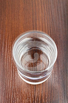 Glass of transparent purified water on wooden table, top view