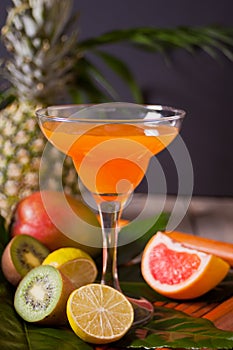 Glass of tropical exotic multifruit juice cocktail drink with fruits nearby