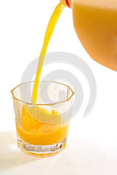 A glass tumbler is being filled with fresh squeezed Florida orange juice
