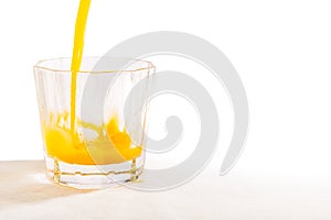 A glass tumbler is being filled with freshly squeezed Florida orange juice