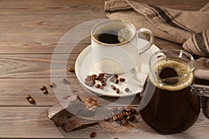 Glass turkish coffee pot, cup of hot drink, chocolate and beans on wooden table, space for text