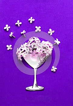 Glass under cocktail drink and lilac flowers on purple background