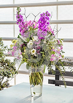 Glass vase with bouquet of beautiful flowers on bright background. Spring natural background. Gift bunch of colorful flowers