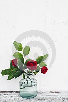 Glass vase with bouquet of roses on vintage table