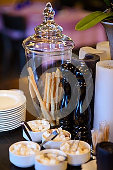 Glass vase with bread snack and decorative candles on the table.