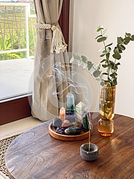 Glass vase with with eucalyptus leaves, various healing crystals and incense stick
